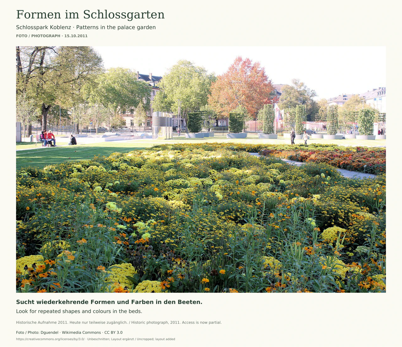 Ein breites Beet voller gelber und orangefarbener Blüten liegt im Vordergrund. Dahinter folgen eine Rasenfläche, einzelne Besucher, große Pflanzkübel und herbstliche Bäume vor Stadtgebäuden. Der Bildrand nennt das Aufnahmedatum 15. Oktober 2011.
