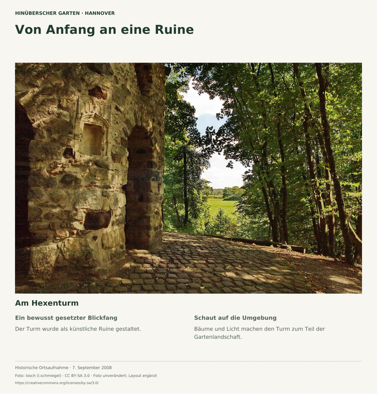 Detail der groben Steinmauer und einer hohen Öffnung des Hexenturms; daneben Kopfsteinpflaster, schattige Bäume und ein Blick ins grüne Offenland.