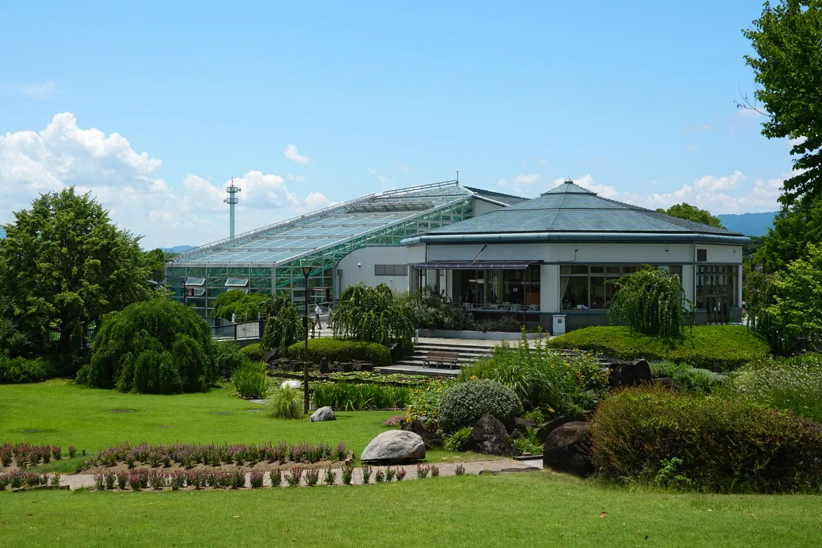 緑の芝生、花壇、岩の向こうに、みずの森のガラス張りの温室と隣接する低層の建物が見える。